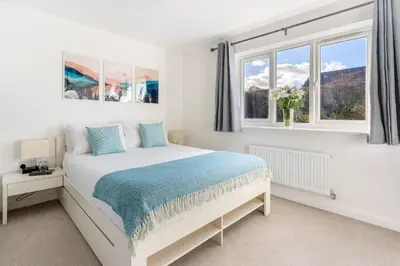a white bedroom with a bed and two windows at Peaceful cottage near beaches - Bickland View in Falmouth