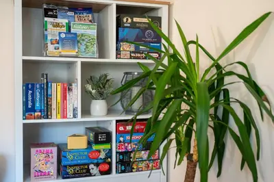 a book shelf filled with books and a potted plant at Peaceful cottage near beaches - Bickland View in Falmouth