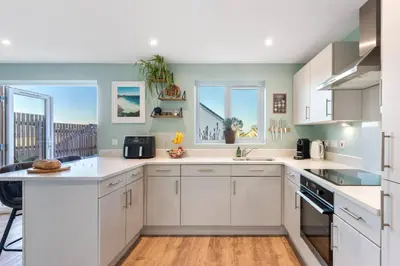 a kitchen with white cabinets and a large window at Peaceful cottage near beaches - Bickland View in Falmouth