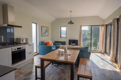 a living room with a table and a blue couch at Middle Barn at Cusgarne Manor, adults only in Cusgarne