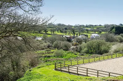 a hill with a fence and a field with houses at Middle Barn at Cusgarne Manor, adults only in Cusgarne