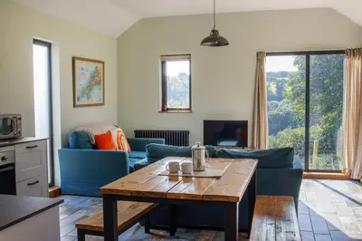 a living room with a blue couch and a table at Middle Barn at Cusgarne Manor, adults only in Cusgarne