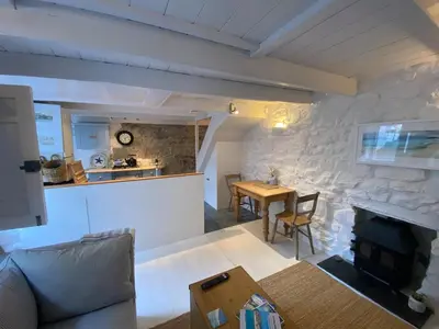 a living room with a fireplace and a table at SEA-AH-NA SIDE COTTAGE - Steps from the Beach Grade II Listed Refurbished Romantic Getaway in St Ives