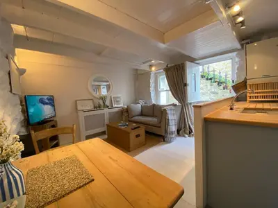 a living room with a table and a couch at SEA-AH-NA SIDE COTTAGE - Steps from the Beach Grade II Listed Refurbished Romantic Getaway in St Ives