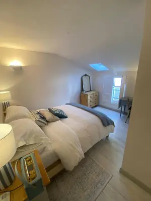 a bedroom with a large bed with white sheets at SEA-AH-NA SIDE COTTAGE - Steps from the Beach Grade II Listed Refurbished Romantic Getaway in St Ives