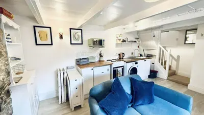 a living room with a blue couch and a kitchen at Waves End - Port Isaac Cornwall in Port Isaac