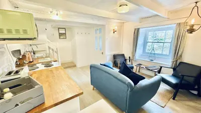 a living room with a blue couch and a tv at Waves End - Port Isaac Cornwall in Port Isaac