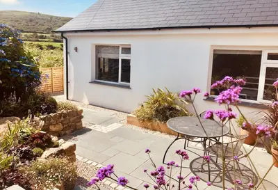 a small white house with a table and flowers at Little Croft- Walking paradise close to St Ives in St Ives