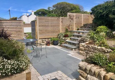 a garden with a table and a wooden fence at Little Croft- Walking paradise close to St Ives in St Ives