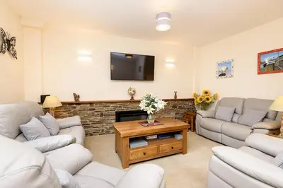 a living room with couches and a flat screen tv at Heart of Looe Apartment in Looe