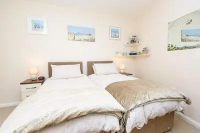 two beds in a bedroom with white walls at Heart of Looe Apartment in Looe