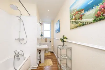 a white bathroom with a sink and a shower at Heart of Looe Apartment in Looe