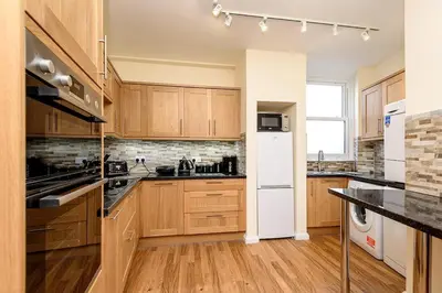 a kitchen with wooden cabinets and a white refrigerator at Heart of Looe Apartment in Looe