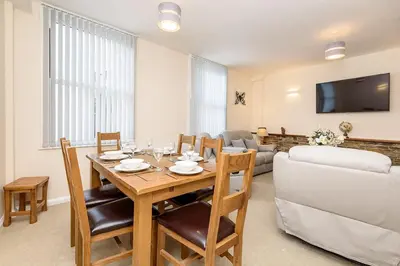 a living room with a table and a couch at Heart of Looe Apartment in Looe