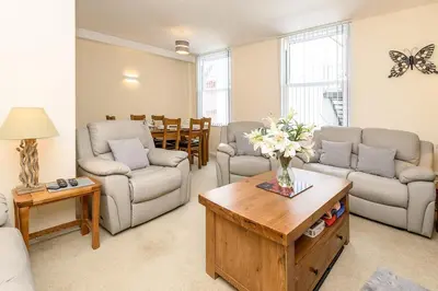 a living room with couches and a table with flowers at Heart of Looe Apartment in Looe
