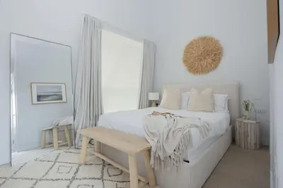 a white bedroom with a white bed and a wooden bench at 10 Cannery Row - Stunning Views - Pet Welcome - Free WiFi & Parking in Hayle