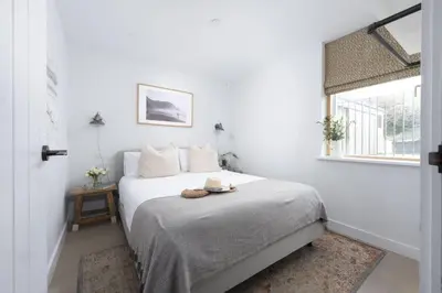 a white bedroom with a bed with a hat on it at 10 Cannery Row - Stunning Views - Pet Welcome - Free WiFi & Parking in Hayle