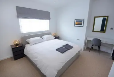 a bedroom with a white bed and a chair at Ebenezer Hall in Falmouth