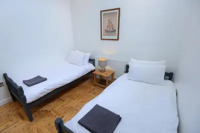 two beds in a room with a small table at Ebenezer Hall in Falmouth