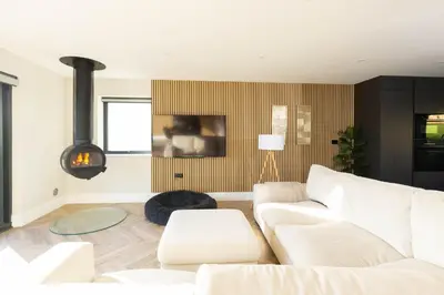 a living room with a white couch and a fire place at Seaglass Point in Mevagissey