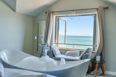 a bathroom with a tub and a window with the ocean at Harbour Lights in Charlestown
