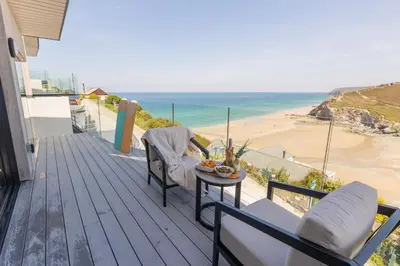 a balcony with a table and chairs and a view of a beach at Ocean Skies in Porthtowan