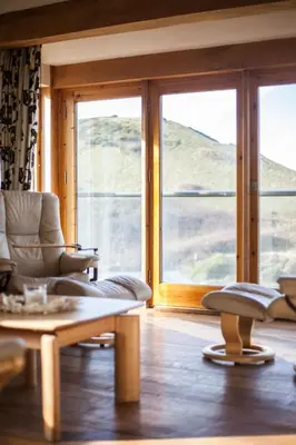 a living room with a couch and a table and windows at Oceans Edge in Portreath