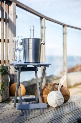 a table with a bucket and wine glasses on a porch at Oceans Edge in Portreath