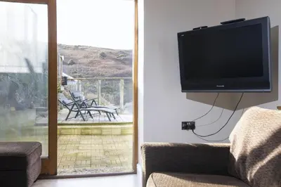 a flat screen tv hanging on a wall next to a patio at Oceans Edge in Portreath