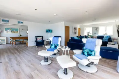 a living room with chairs and a blue couch at The Lookout in Portreath