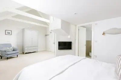a white bedroom with a bed and a tv at The Tide House in St Ives