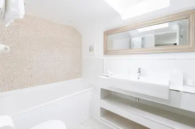 a white bathroom with a sink and a mirror at The Tide House in St Ives