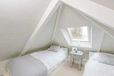 a attic bedroom with two beds and a window at The Tide House in St Ives