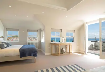 a bedroom with a bed and a view of the ocean at The Tide House in St Ives