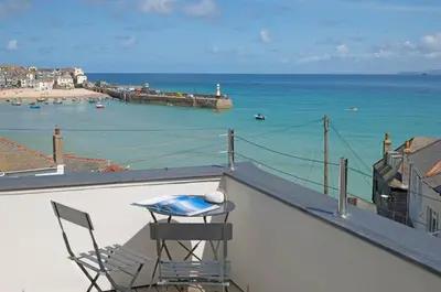 a table and a chair on a balcony overlooking the ocean at The Tide House in St Ives