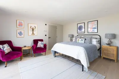 a bedroom with a bed and two chairs at Tamarisk in Portreath