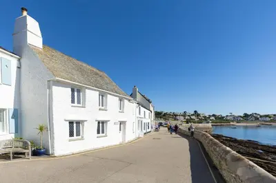 a group of people walking down a sidewalk next to a building at The Old Courthouse in Saint Mawes