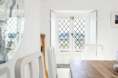 a dining room with a table and two windows at The Old Courthouse in Saint Mawes