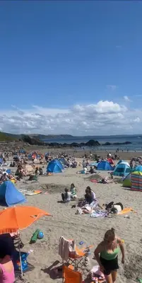 a crowd of people on a beach with umbrellas at Entire house by East Looe beach in Looe