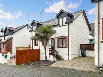 a white house with a fence and a palm tree at 4 Porth Cottages in Saint Columb Minor
