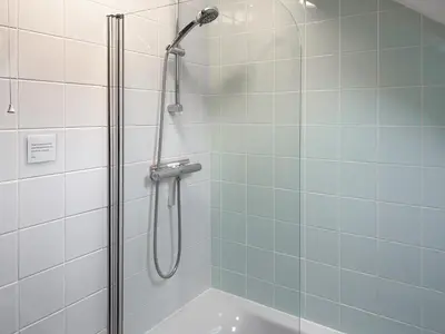 a bathroom with a shower with a glass door at 4 Porth Cottages in Saint Columb Minor