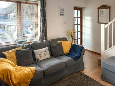 a living room with a gray couch with yellow pillows at 4 Porth Cottages in Saint Columb Minor