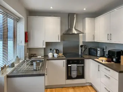 a kitchen with white cabinets and a sink at 4 Porth Cottages in Saint Columb Minor