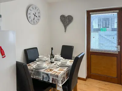 a dining room table with chairs and a clock on the wall at 4 Porth Cottages in Saint Columb Minor