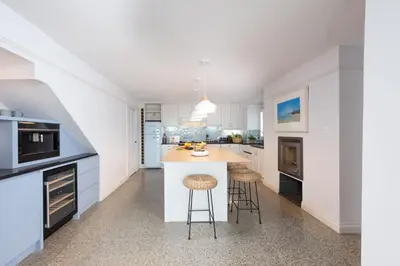 a kitchen with white cabinets and a island with bar stools at Watergate View in Porth