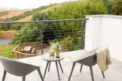 a patio with two chairs and a table with a bottle of wine at Watergate View in Porth