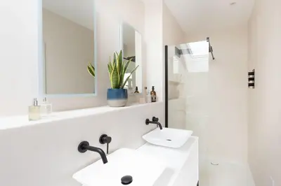 a white bathroom with two sinks and a mirror at Watergate View in Porth