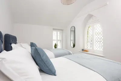 a white bedroom with two beds and a window at Watergate View in Porth