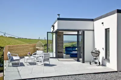 a house with a patio with chairs and a grill at Watergate Horizon in Porth