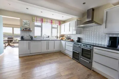 a kitchen with white cabinets and stainless steel appliances at Trewalder in St Merryn